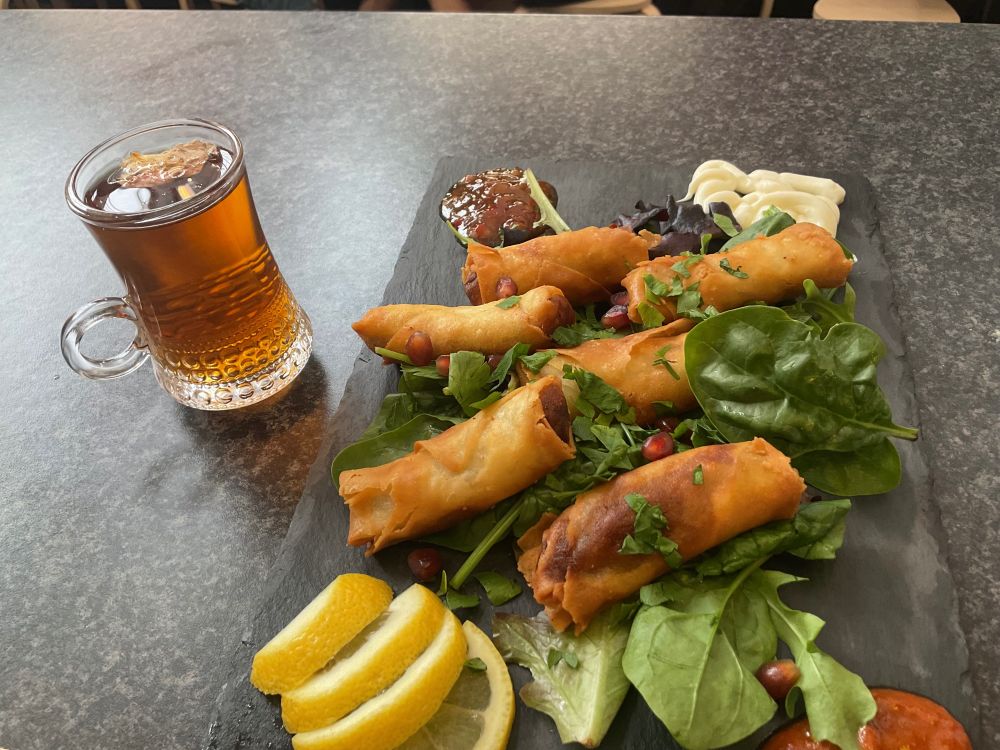 Moroccan food: duck spring rolls, with salad and pomegranate seeds. Tea with a rose petal