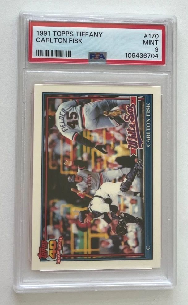 Image of a 1991 Topps Tiffany, Carlton Fisk. Card shows Fisk on left side of image at plate receiving a thrown ball, as Cecil Fielder runs toward home on right side of image