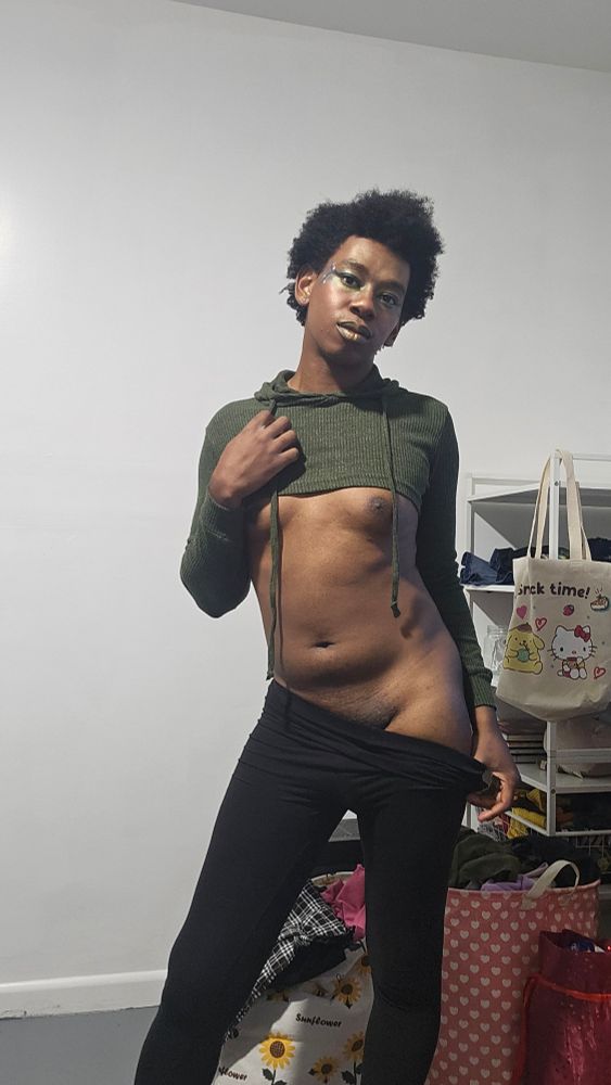 A pinup picture of Rhxie in a green crop hoodie so small her tits are completely exposed and black leggings teasingly pulled down to one side revealing her hip and pelvis 🦋