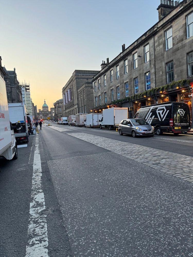 Lots of white vans parked left and right in a street 