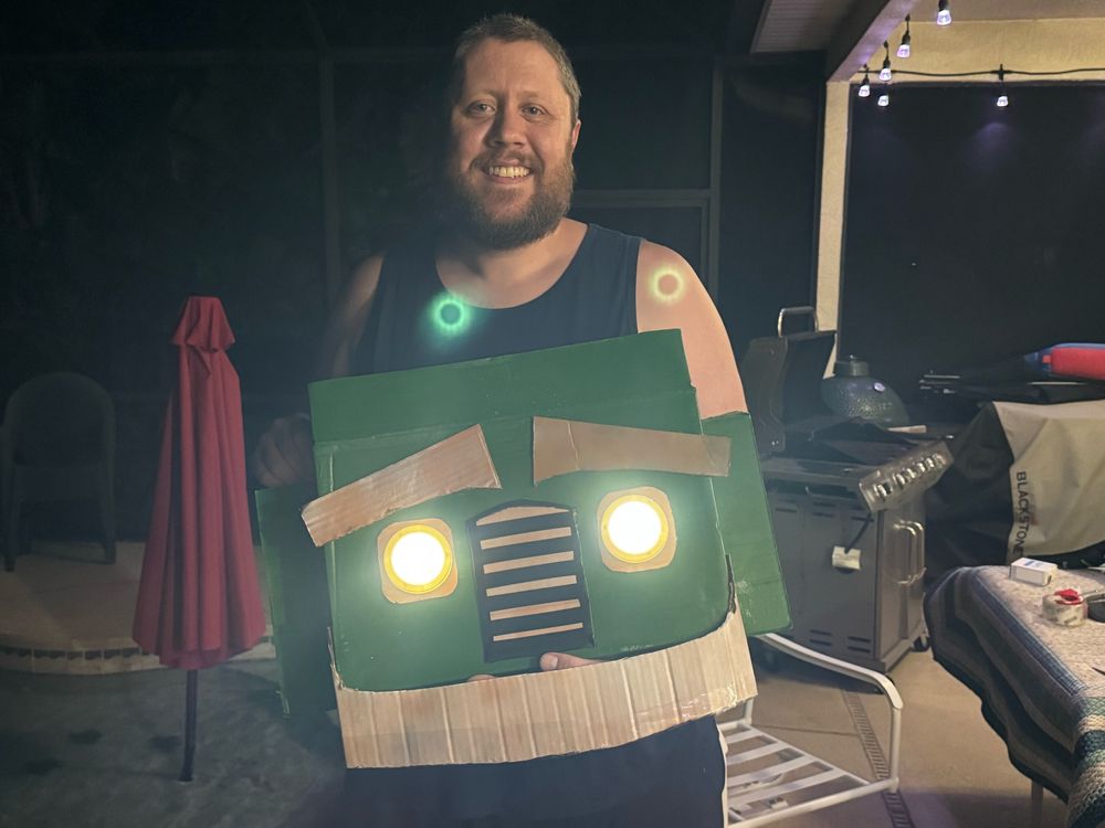 Me holding the head of the Trash Truck costume I made with the headlights lit 