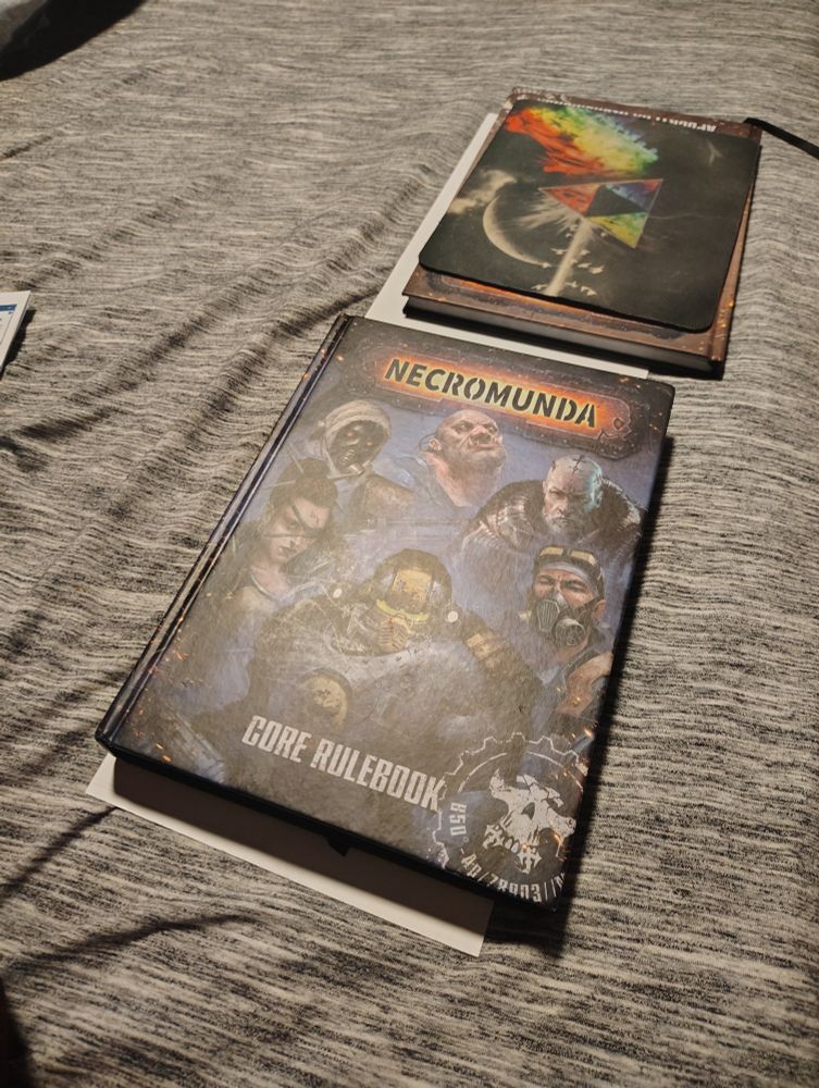 A poster, under a pair of necromunda rulebooks. 