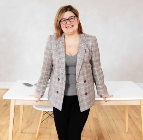 Photo of Matisse Hamel-Nelis standing in front of a white desk.