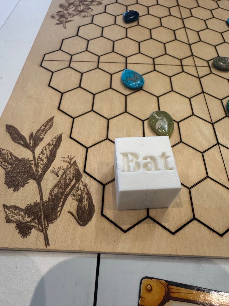 3D printed dice and wood game board laser cut in a honeycomb pattern. 