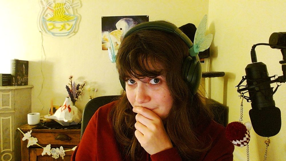 Aleita face à la caméra avec des ailes de libellules accrochées à son casque audio