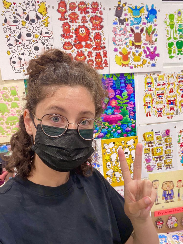 A photo of me in front of my artist alley table 