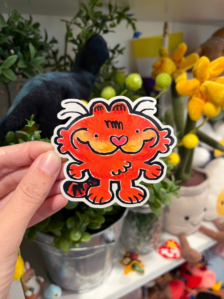 A picture of a hand holding up a Garfield sticker
