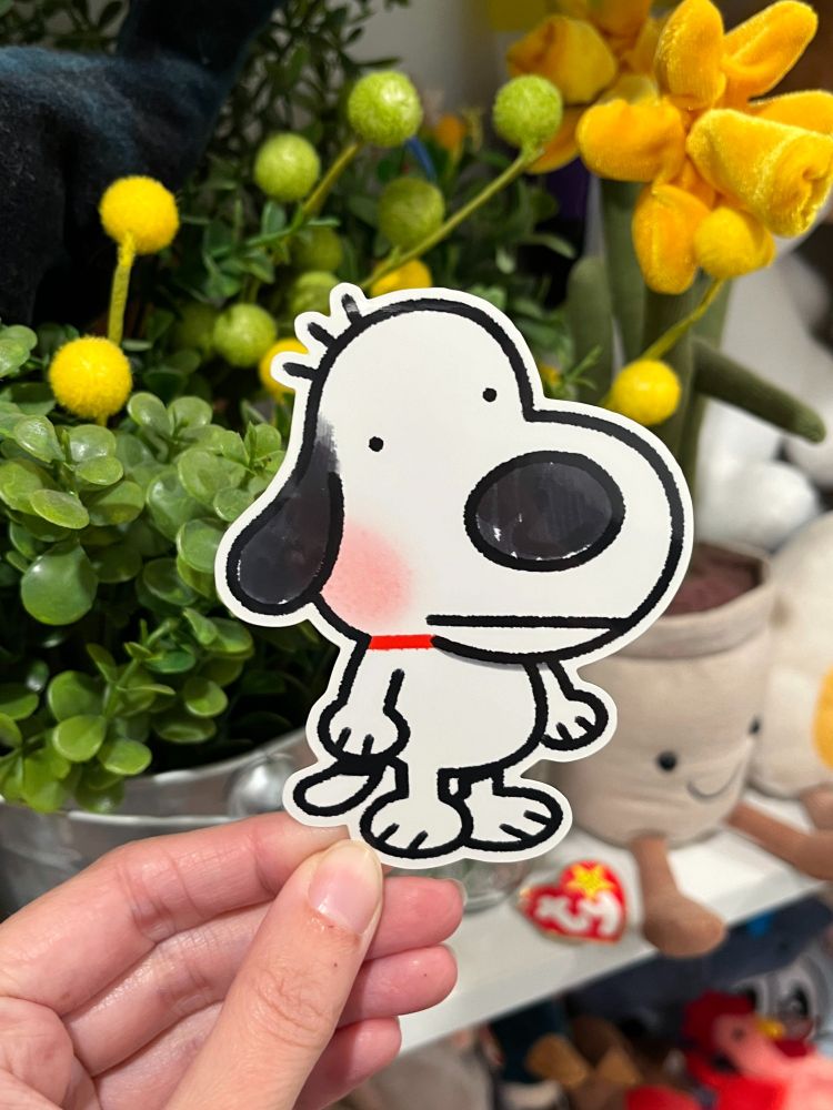 A hand holding up a black and white dog sticker!