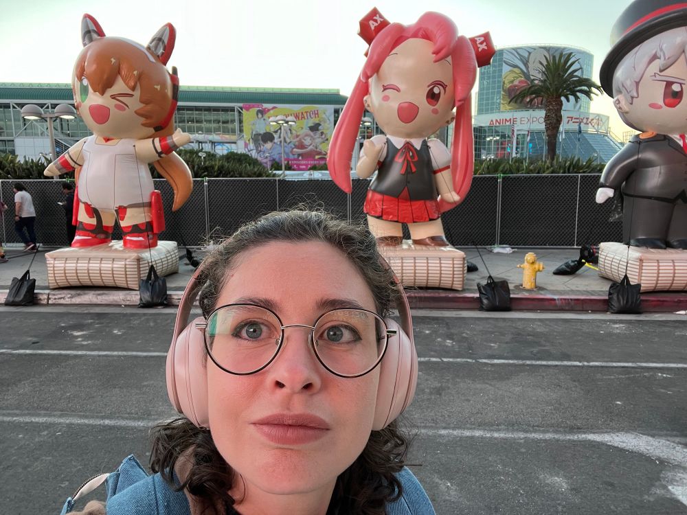 A photo of me on the street in front of giant anime figures 
