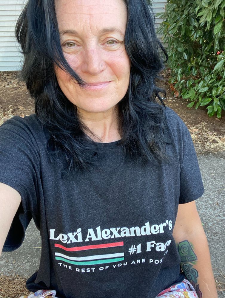 Picture of my ugly mug wearing a T-shirt that says Lexi Alexander’s number one fan. The rest of you are posers and it’s in a kind of retro vintage design style with four stripes on it in the colors of the Palestine flag.