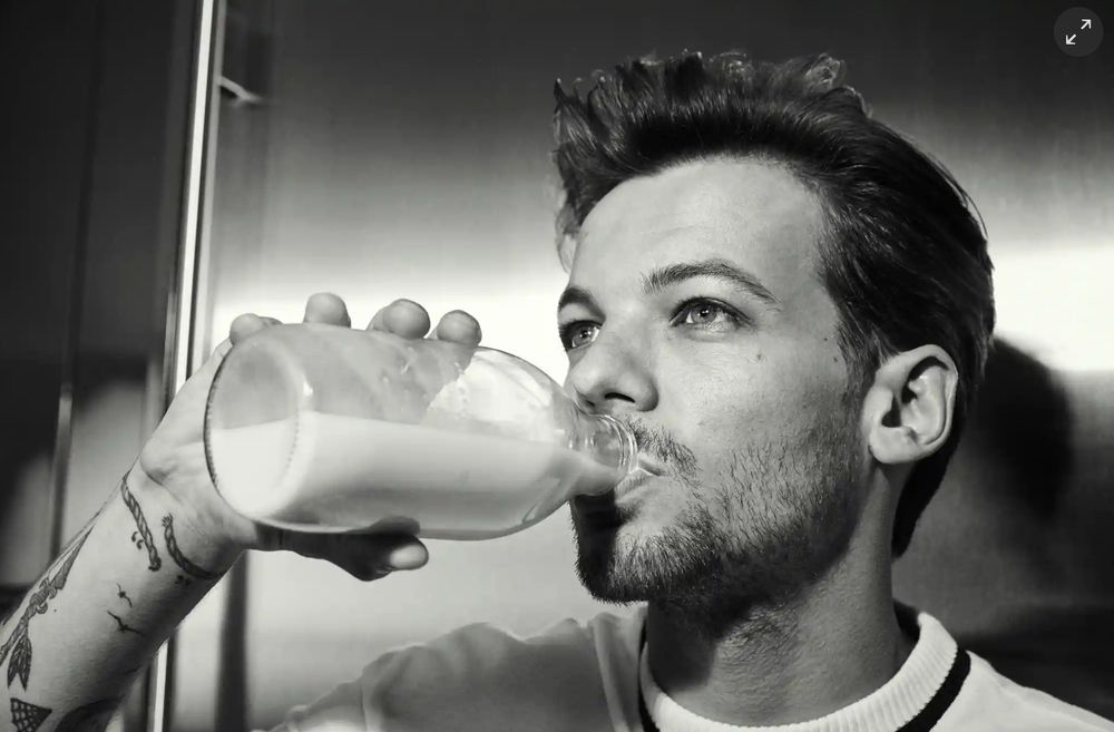 Louis Tomlinson drinking milk and looking into the distance