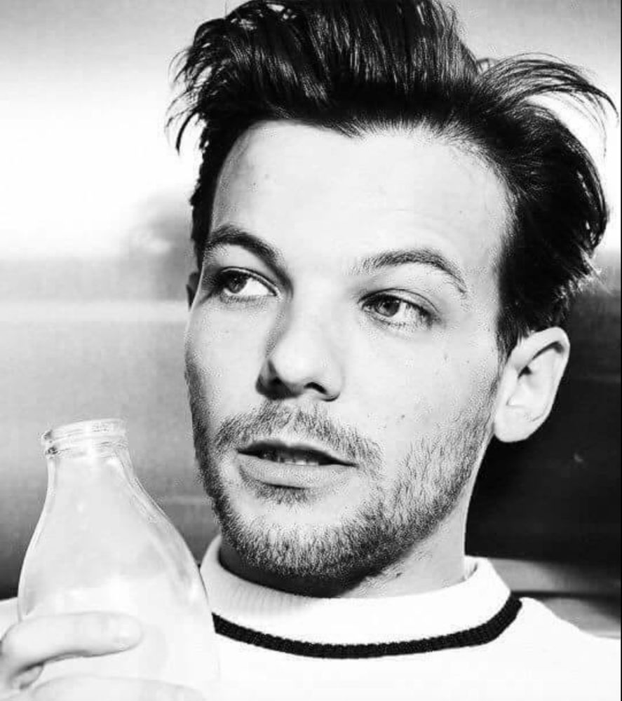 Louis Tomlinson with a bottle of milk, looking quizzical