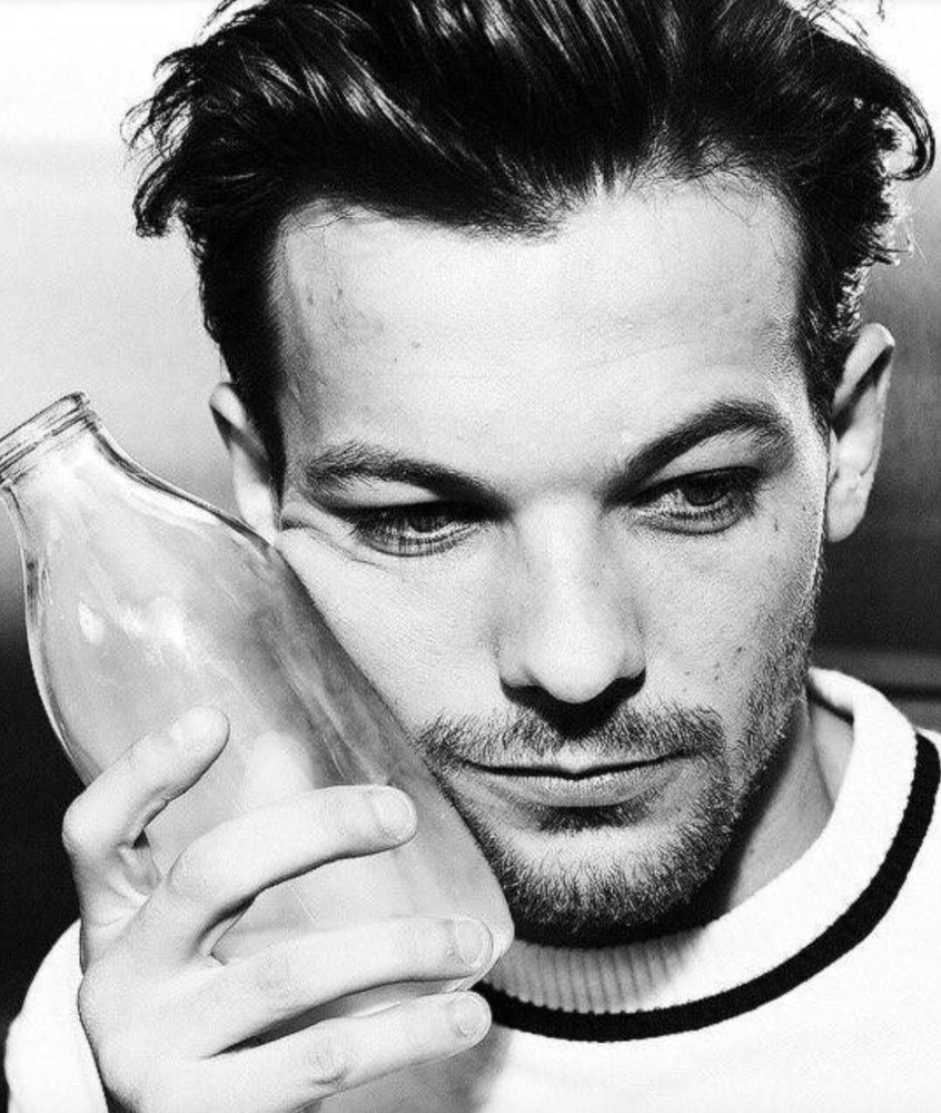 Louis Tomlinson cradling a bottle of milk to his face
