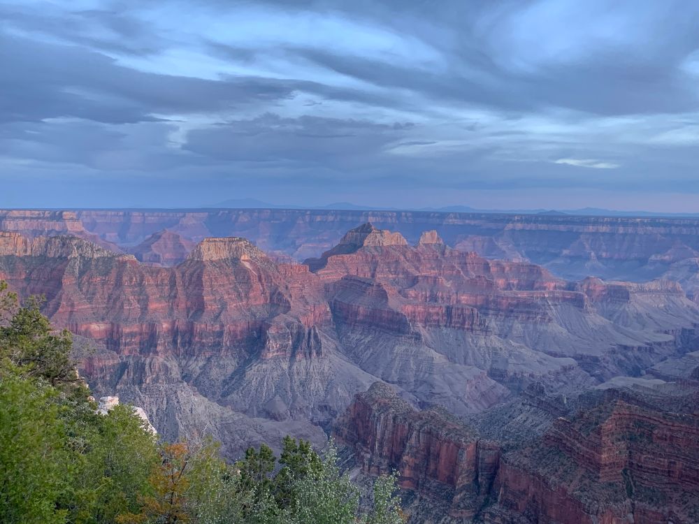 A view of the North Rim of the Grand Canyon at sunrise on a cloudy morning. 