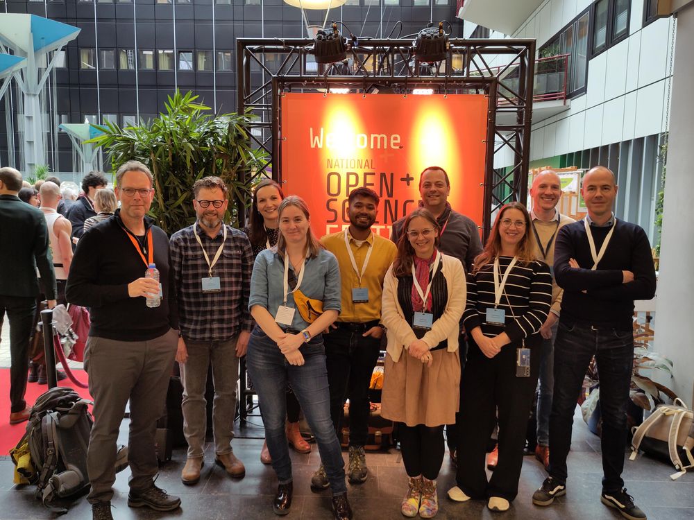 Photo of a group of people in frant of an orange National Open Science Festival board at the festival in Groningen in 2025. The group consists of 10 people from Maastricht University.