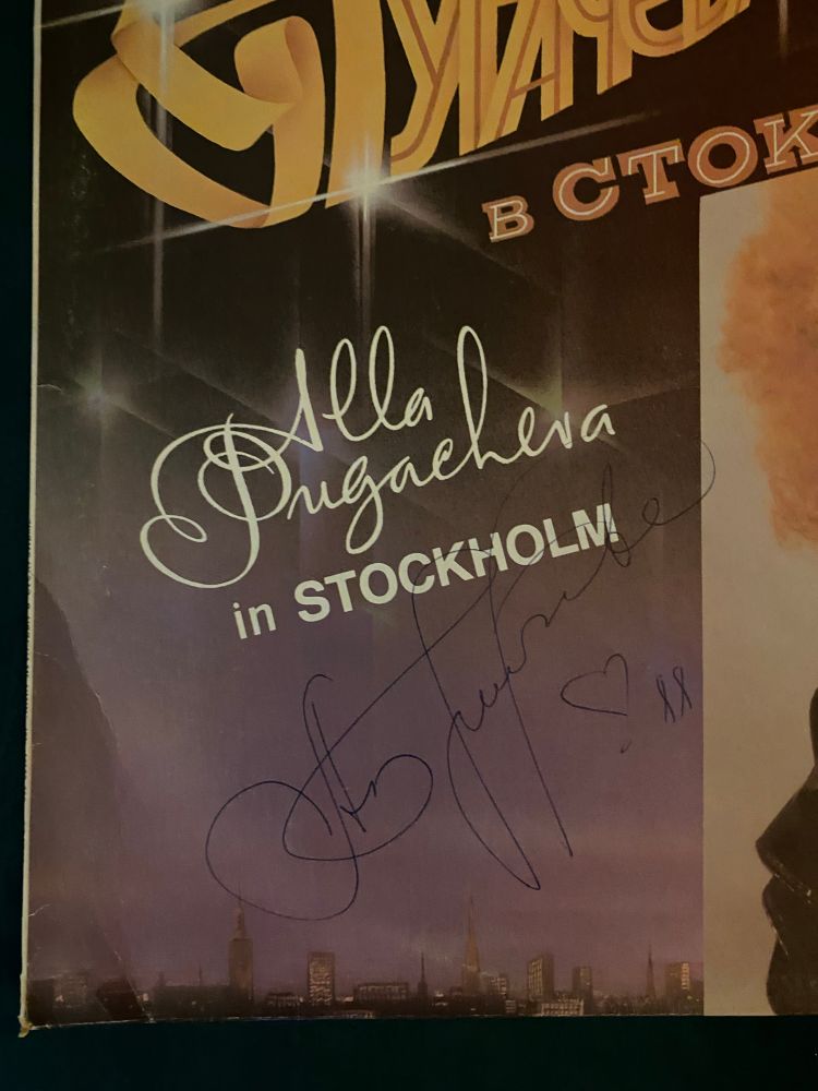bottom left corner of the front cover of Alla Pugacheva in Stockholm, these words in white text on a starry purple night city scene, below that in blue pen is Alla’s signature, a heart, and 88