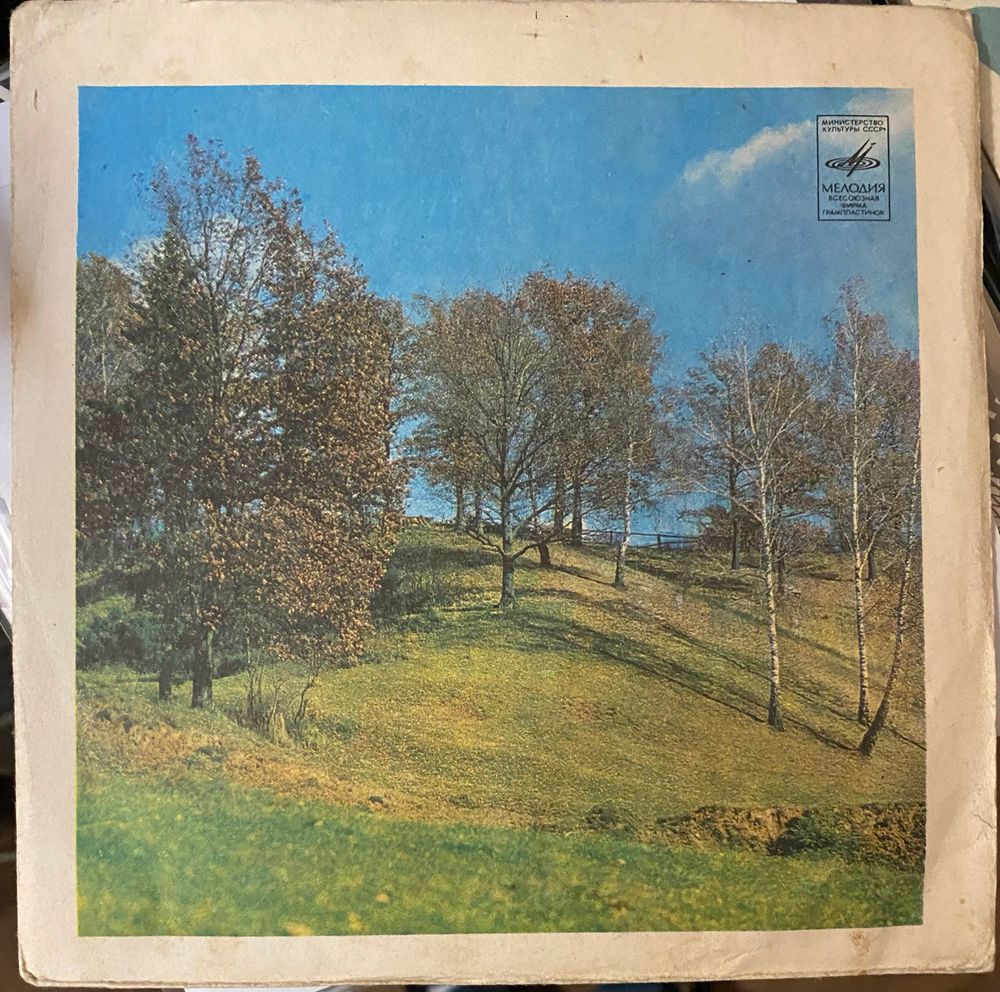 generic soviet 7” record sleeve from the mid 1970s. it’s a green grassy hill with a few trees and a bright blue sky behind it 