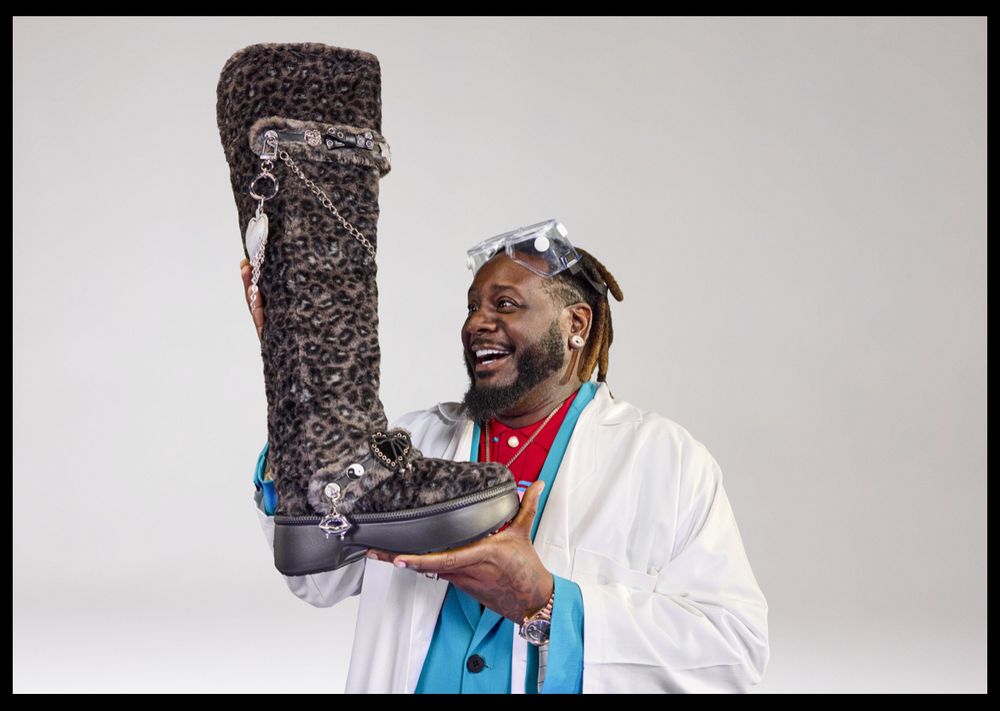 T-Pain with the Crocs Classic Unfurgettable Leopard Knee High Boot, holding the boot aloft and looking delighted and horrified at what he has wrought upon the world 