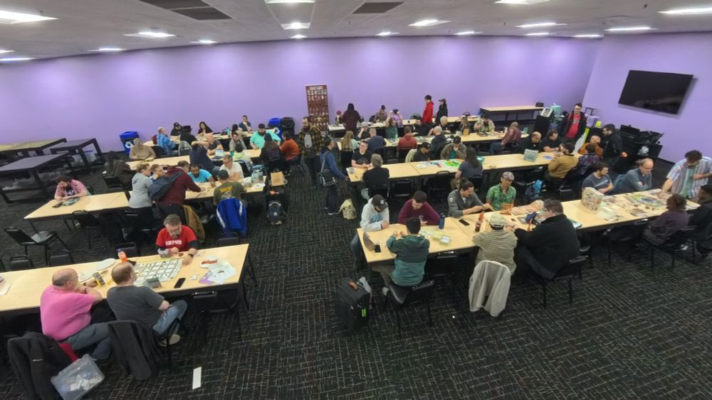 An aerial view of the Unpub OP Kickoff Party, many people are sitting at tables playing games.