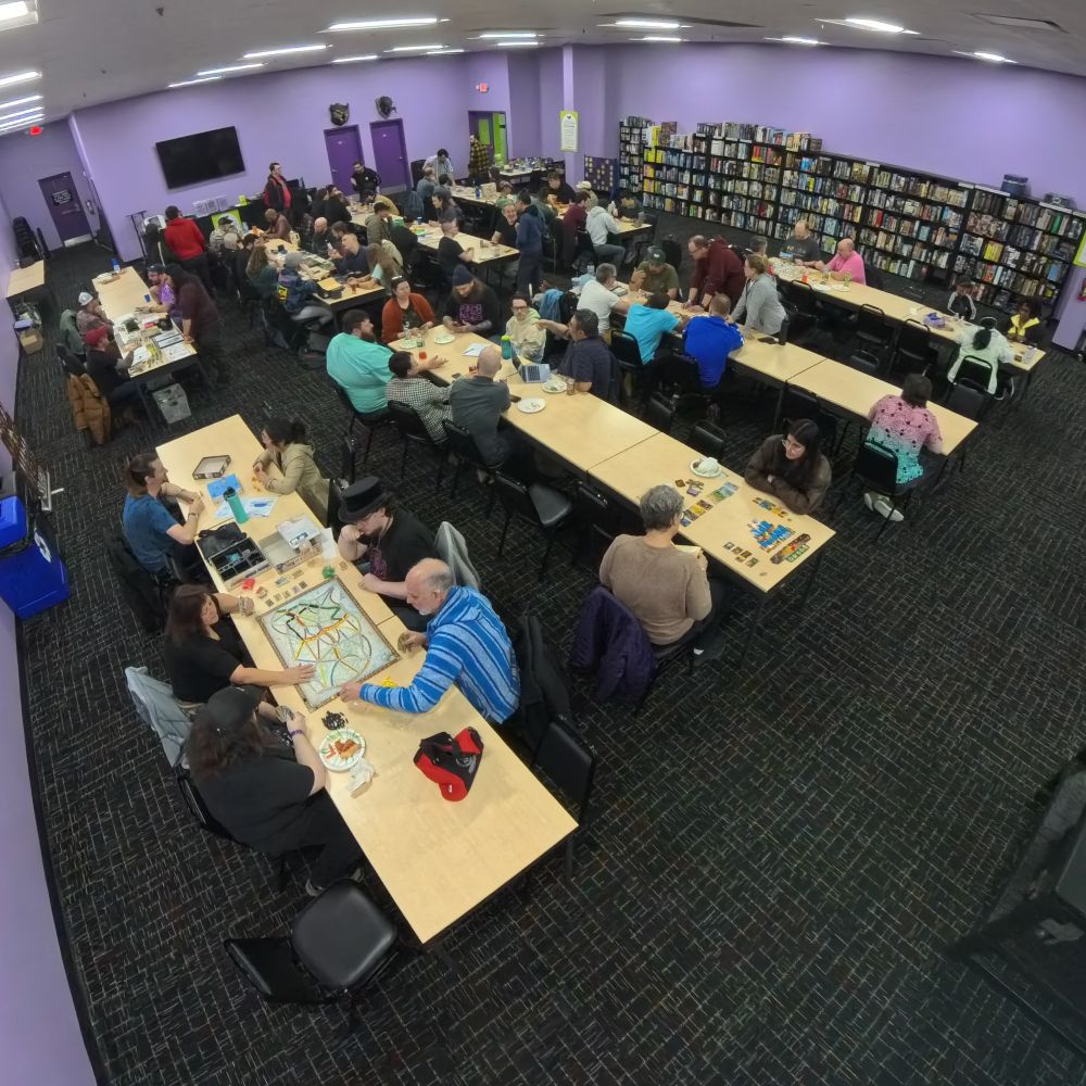 An aerial view of the Unpub OP Kickoff Party, many people are sitting at tables playing games.