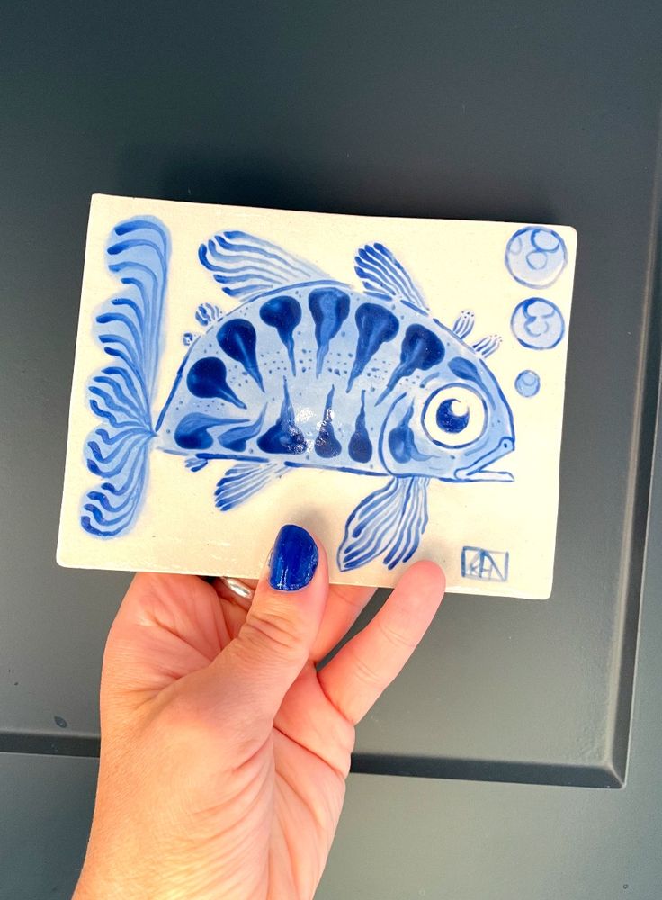 A blue illustrative fish tile with long fins and a fun expression