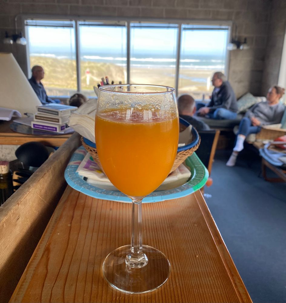 Mimosa in a rustic beach house, with chatting friends and the ocean in the distance 