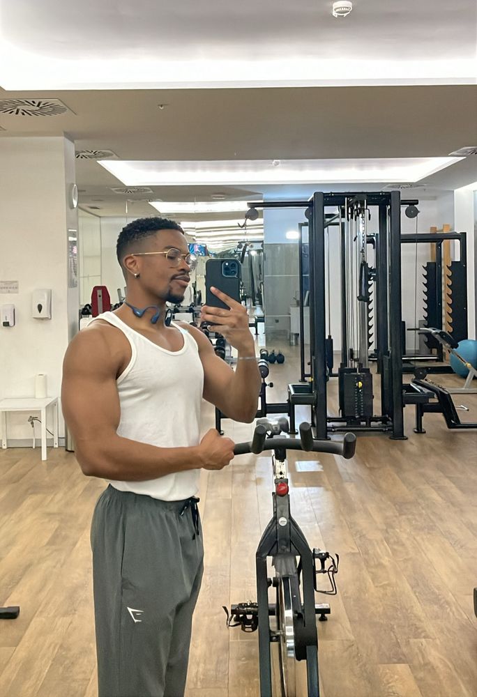 Me looking fine flexing in a white tank after a chest/tricep workout in a Lisbon hotel gym