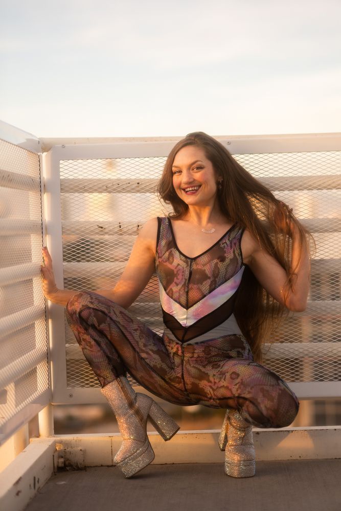 Full body portrait of Goldie kneeling in stairway, soft sun light from left of frame