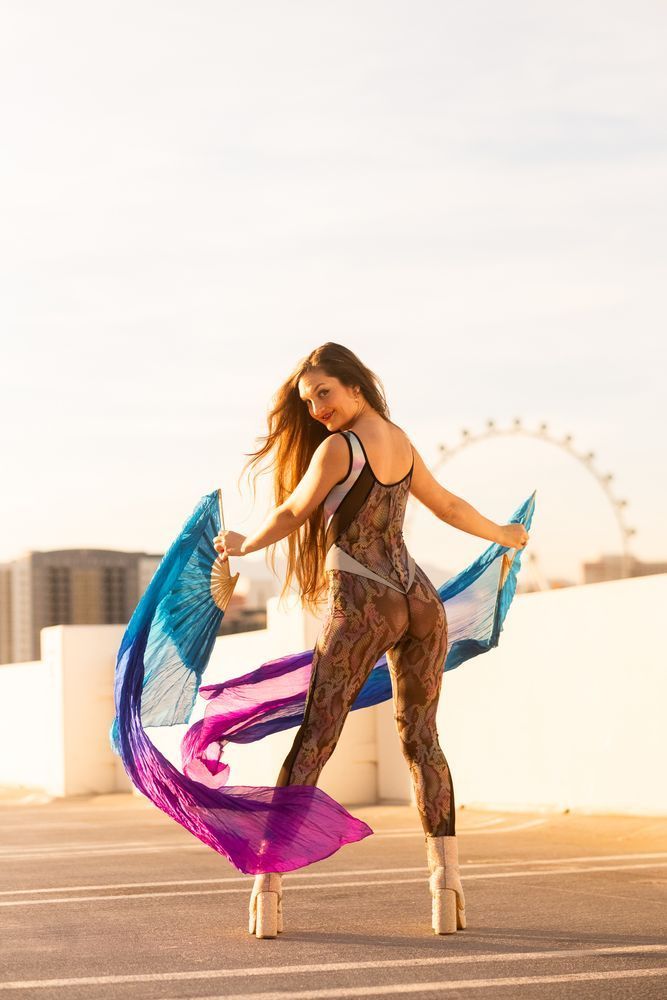 Golden with blue/purple long fans, looking back to camera over shoulder wearing textured bodysuit