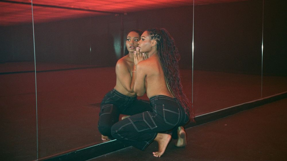 #photography of Addis in mirror, infinity ceiling of red above, her in jeans and looking side of camera 