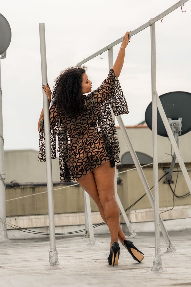 Patterned robe on Syenite on rooftop, leaning on white industrial parts