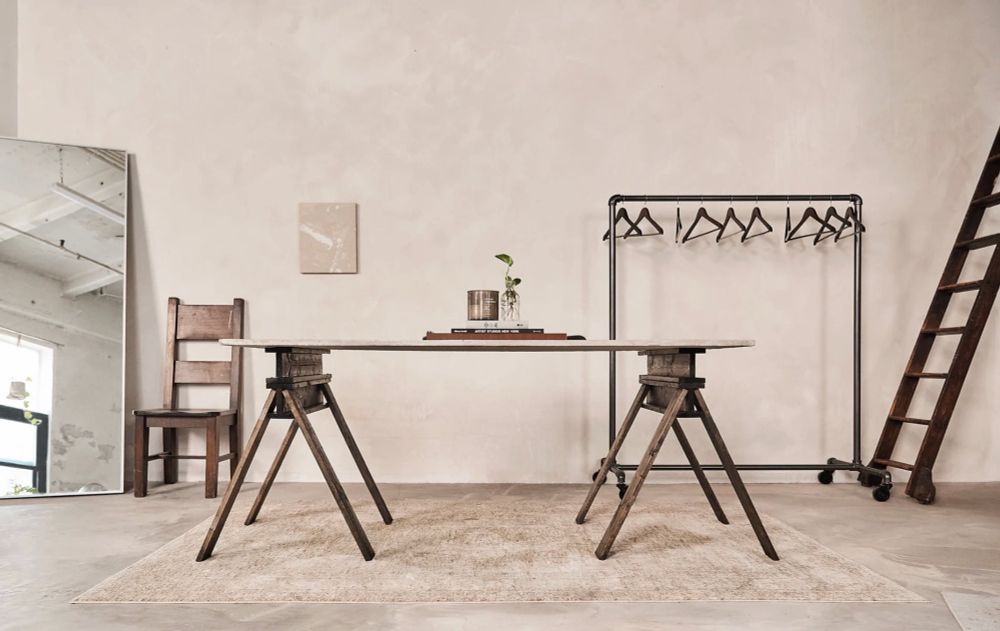Photo studio with white walls and dark furniture such as table hangers and ladder 