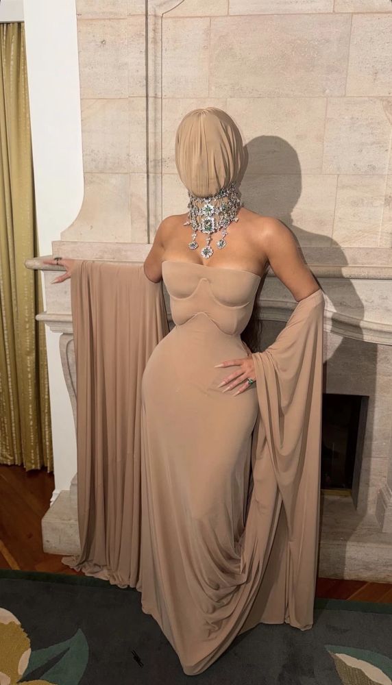 Kim Kardashian usando vestido drapeado bege com uma máscara facial combinando.