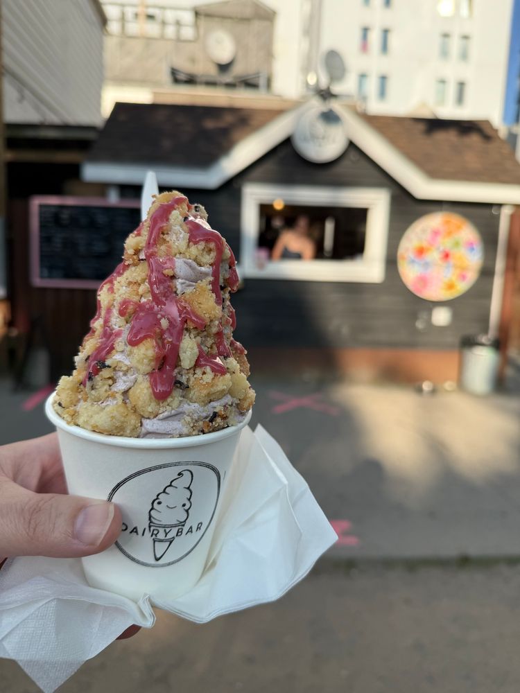 “Hibiscus Sour” sundae with hibiscus soft serve, hibiscus shortbread, and hibiscus curd. The sundae is in a cup held up in front of Dairy Bar. 