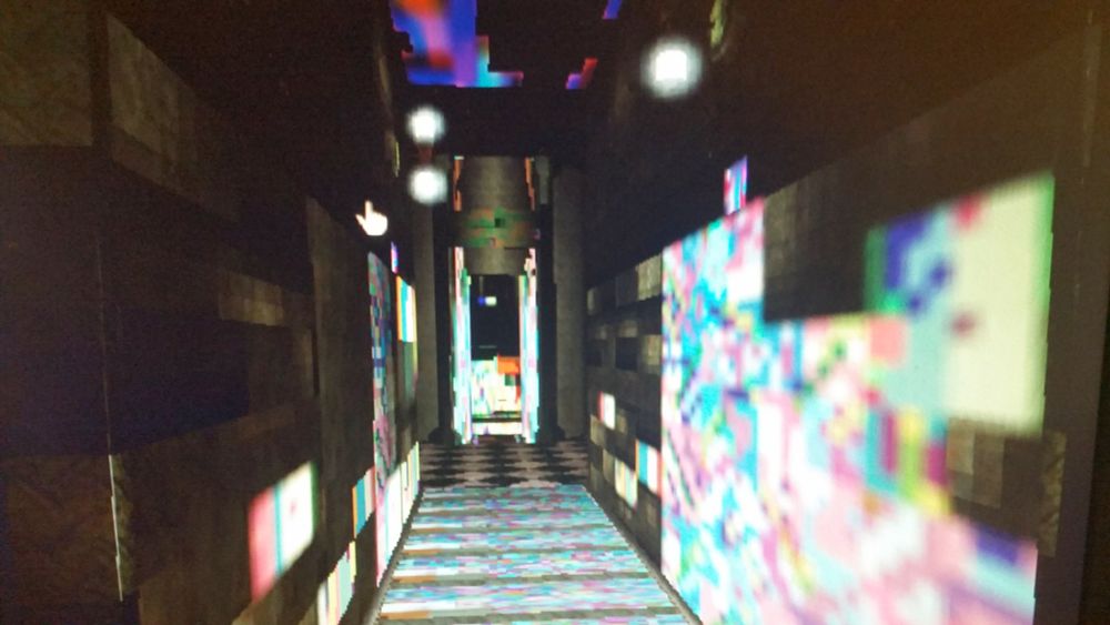 a previously metallic hallway with rectangular glowing patterns, like a cross between a glitch art installation and a lazer tag venue