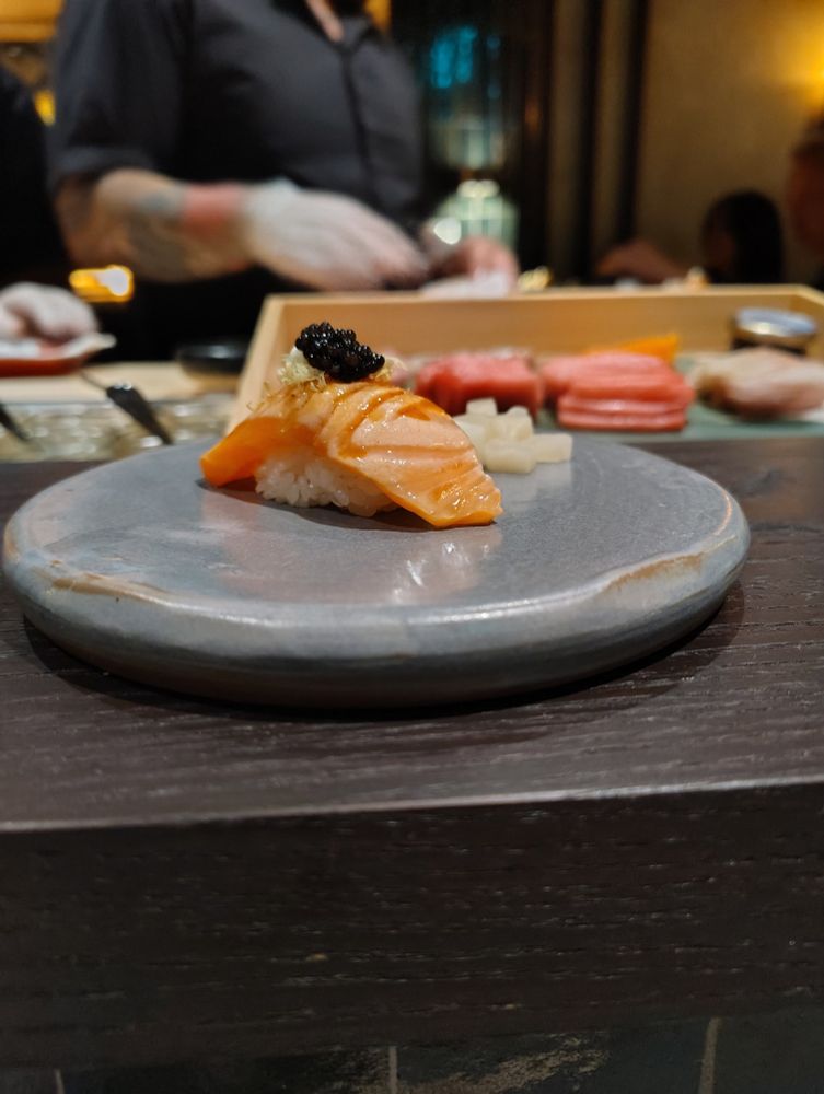 Sushi and ginger on a silver plate. In the background a man in a black buttoned down shirt