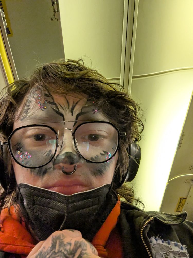 Penn on a plane with face painted to look like a wolf with glitter