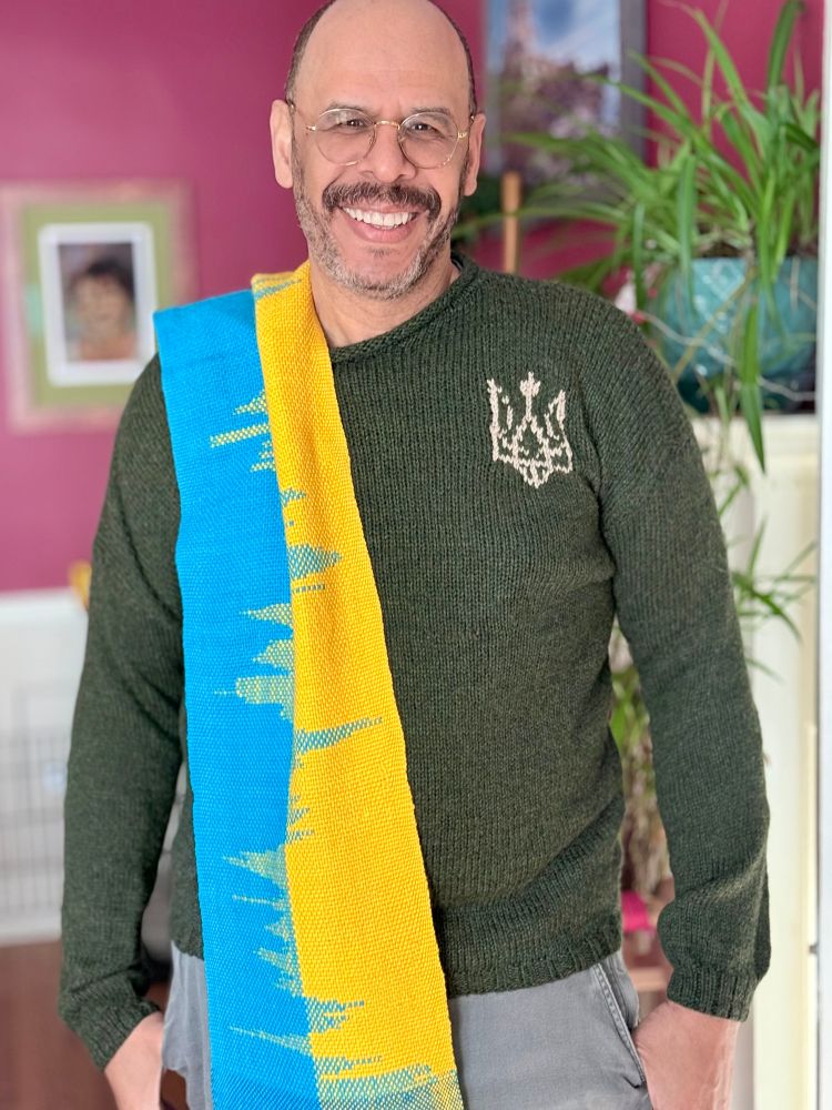 Man wearing sweater with the Ukraine Coat of Arms and a blue and yellow handwoven scarf. 