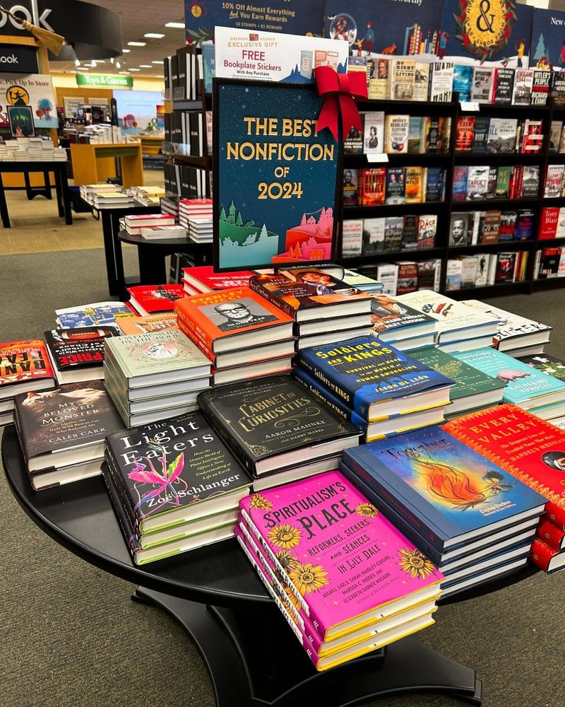 A table in Barnes & Noble with the "The Best Nonfiction of 2024" on top of a bunch of books; with Spiritualism's Place in the right left corner. 