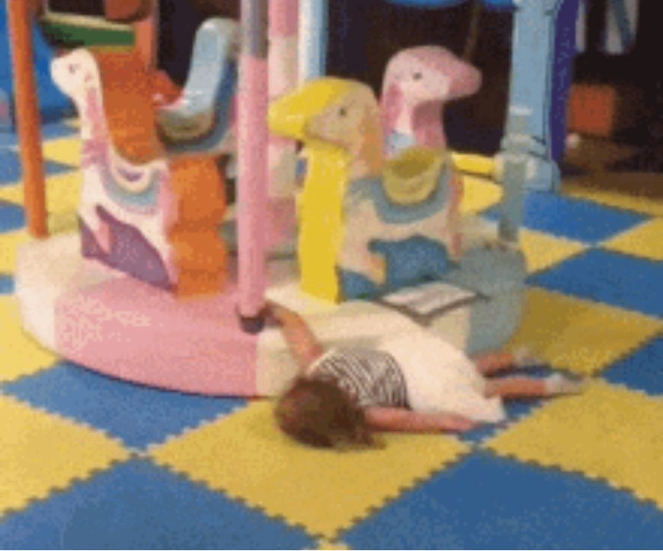 Still frame from gif of a child face down asleep as she gets dragged by a carousel