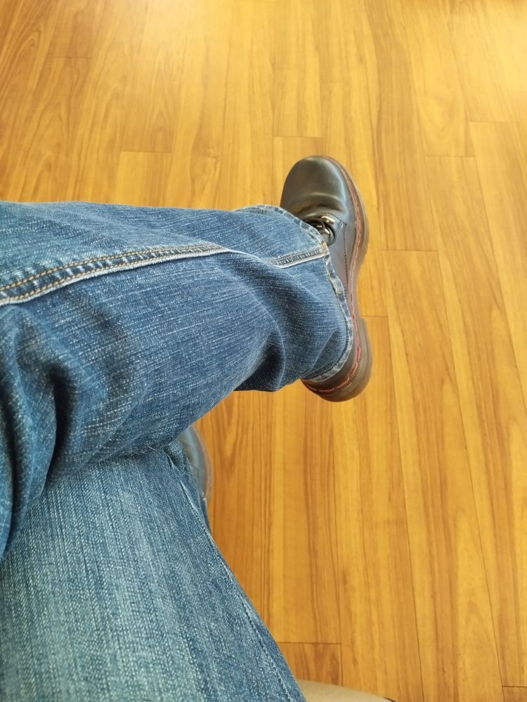 Fußboden mit Holzoptik, Bein in Jeans, blauer Schuh.