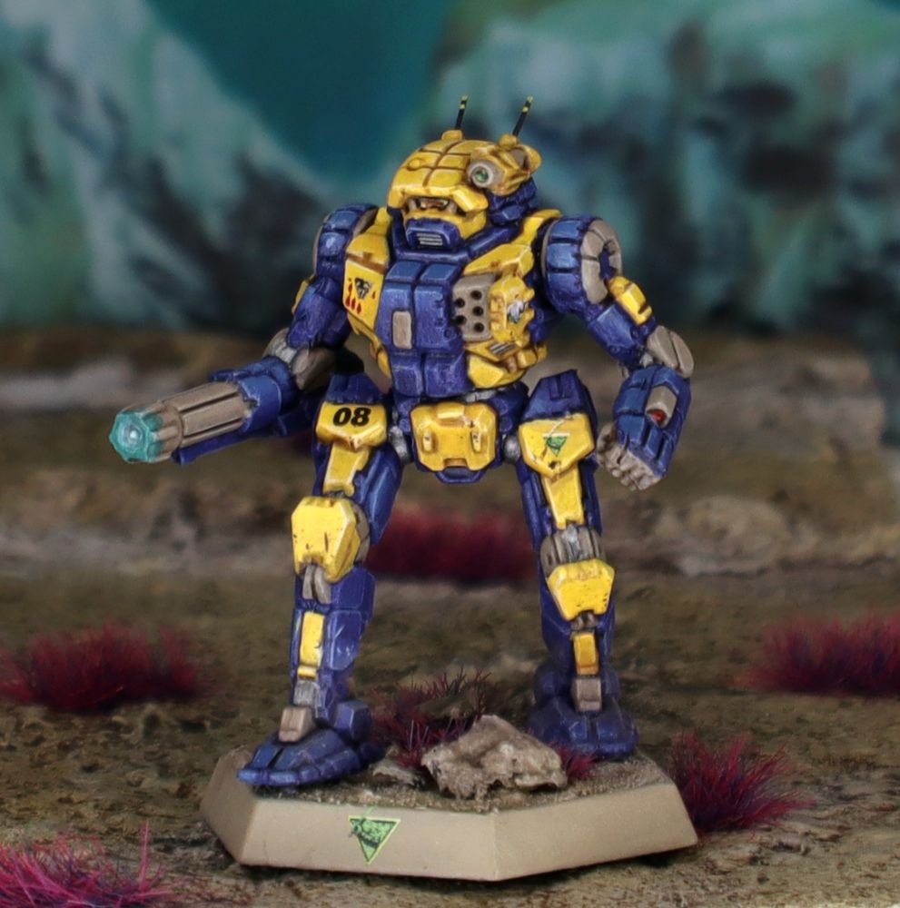 A miniature Vindicator BattleMech painted in blue and yellow, standing atop an alien landscape