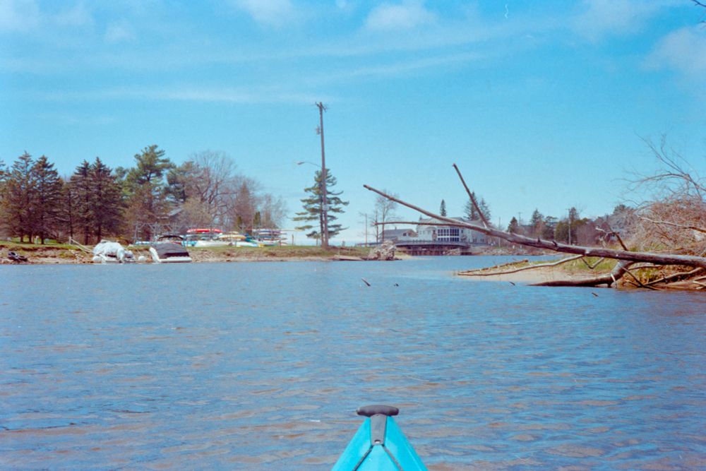 A color film photo taken from a kayak on the Lincoln River, showing the kayak and boat launch area for the Epworth gated community in Ludington, MI