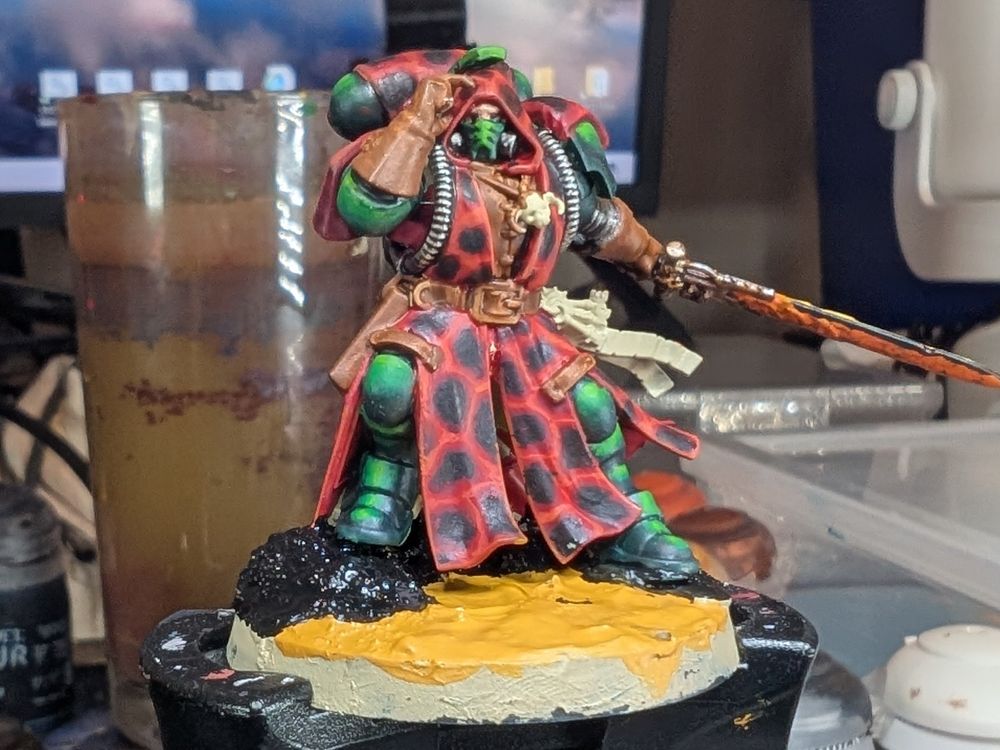 A dark angels librarian wearing a lava coloured camo cloak.