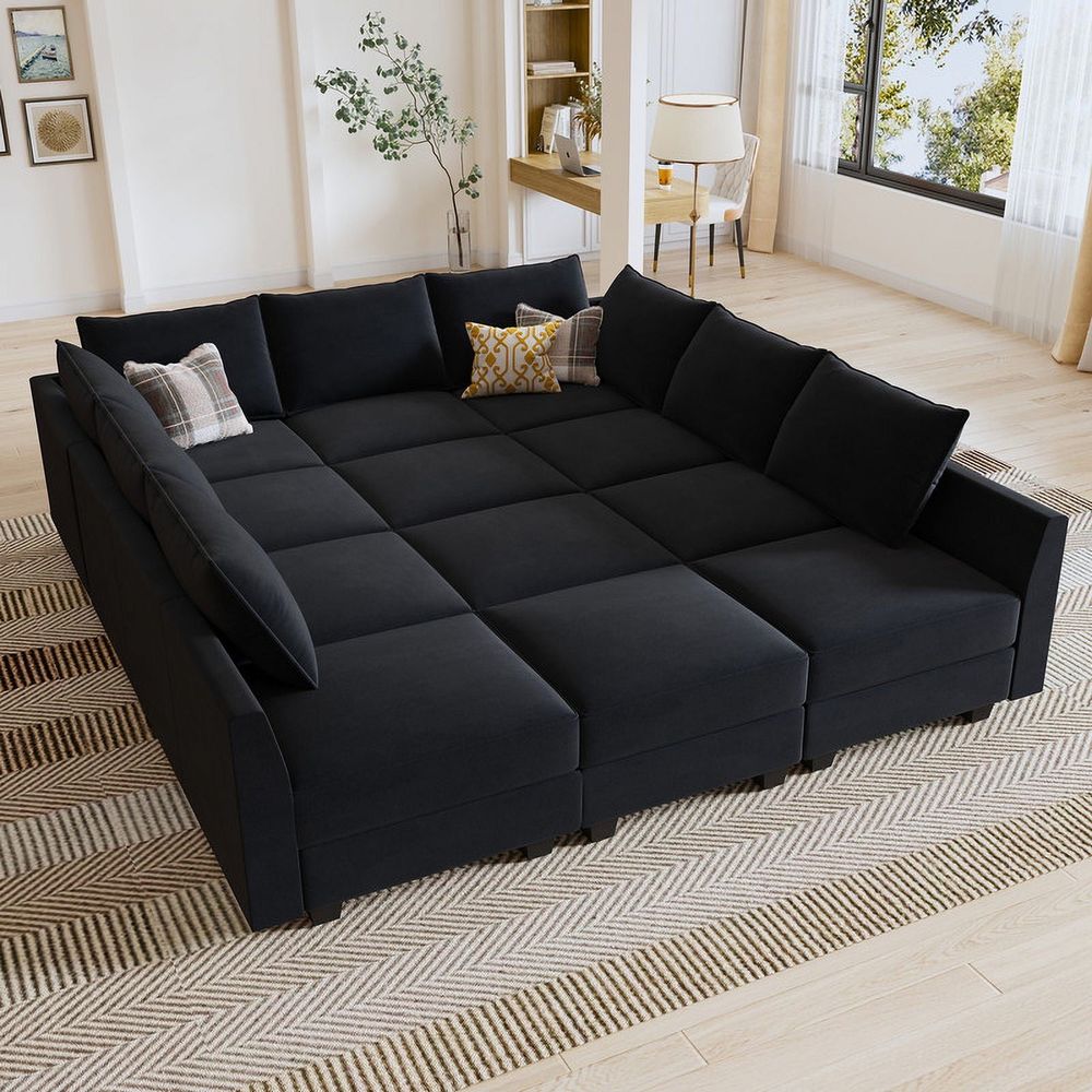 Photo of a modular black sectional couch, approximately four ottomans deep and massive. Looks more like a huge bed than a couch.