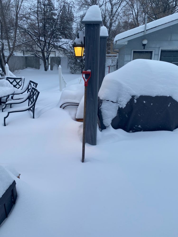 Deck and shovel under several feet of snow.