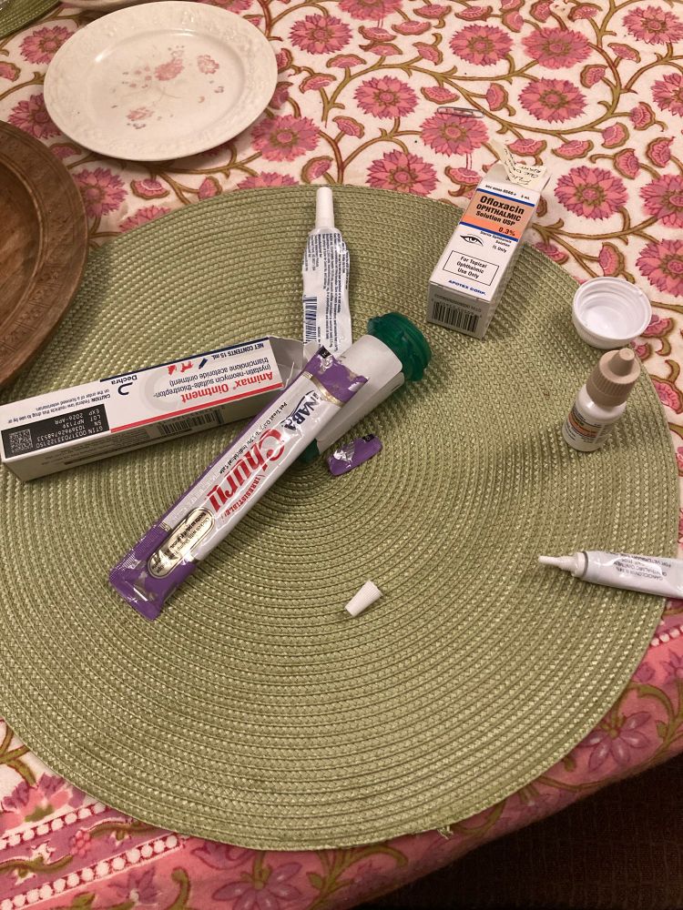 My place at dinner strewn with my cat’s various eye and skin medications and a churu.