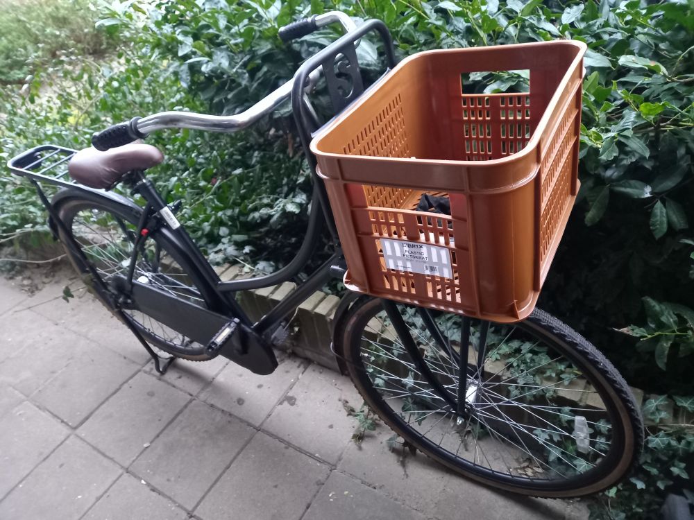 Black oma fiets with a brown crate as a basket.
