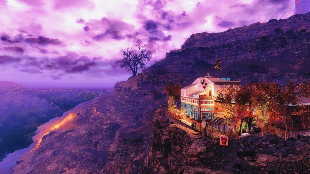 My studio camp in the Ash Heap, brightly against a barren mountain and sooty purple sky. Taken in Fallout 76 by Bethesda game studios