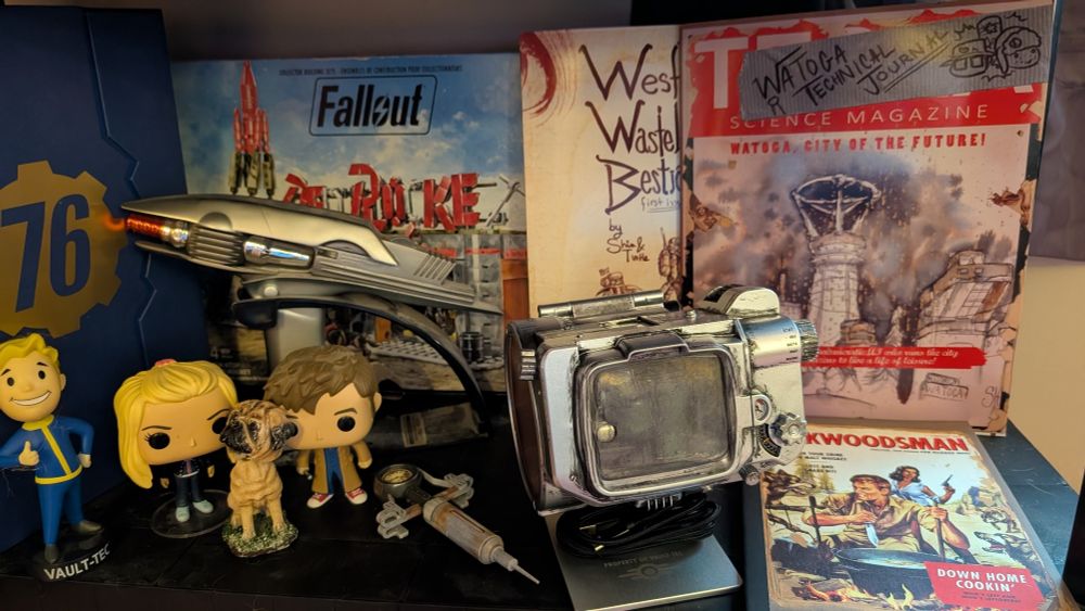 A collectible shelf featuring 76 collector's edition, TV pip-boy, Wasteland bestiary and Watoga technical journal among other prizes